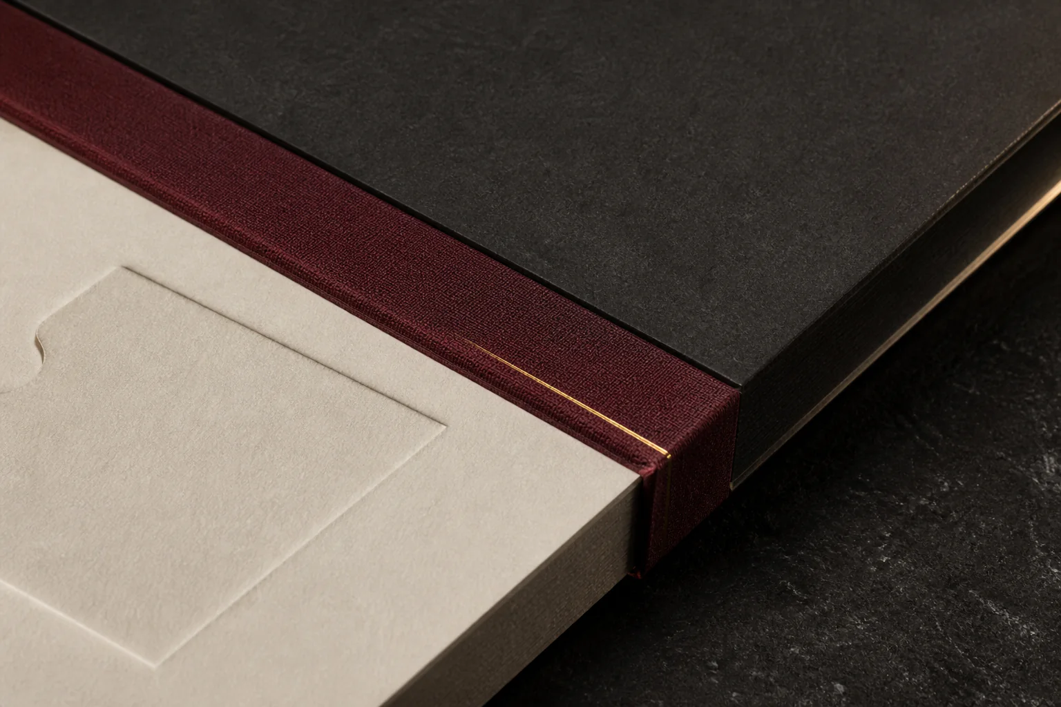 Macro illustrative study of ivory, oxblood and graphite paperboard layers with a fine metallic line